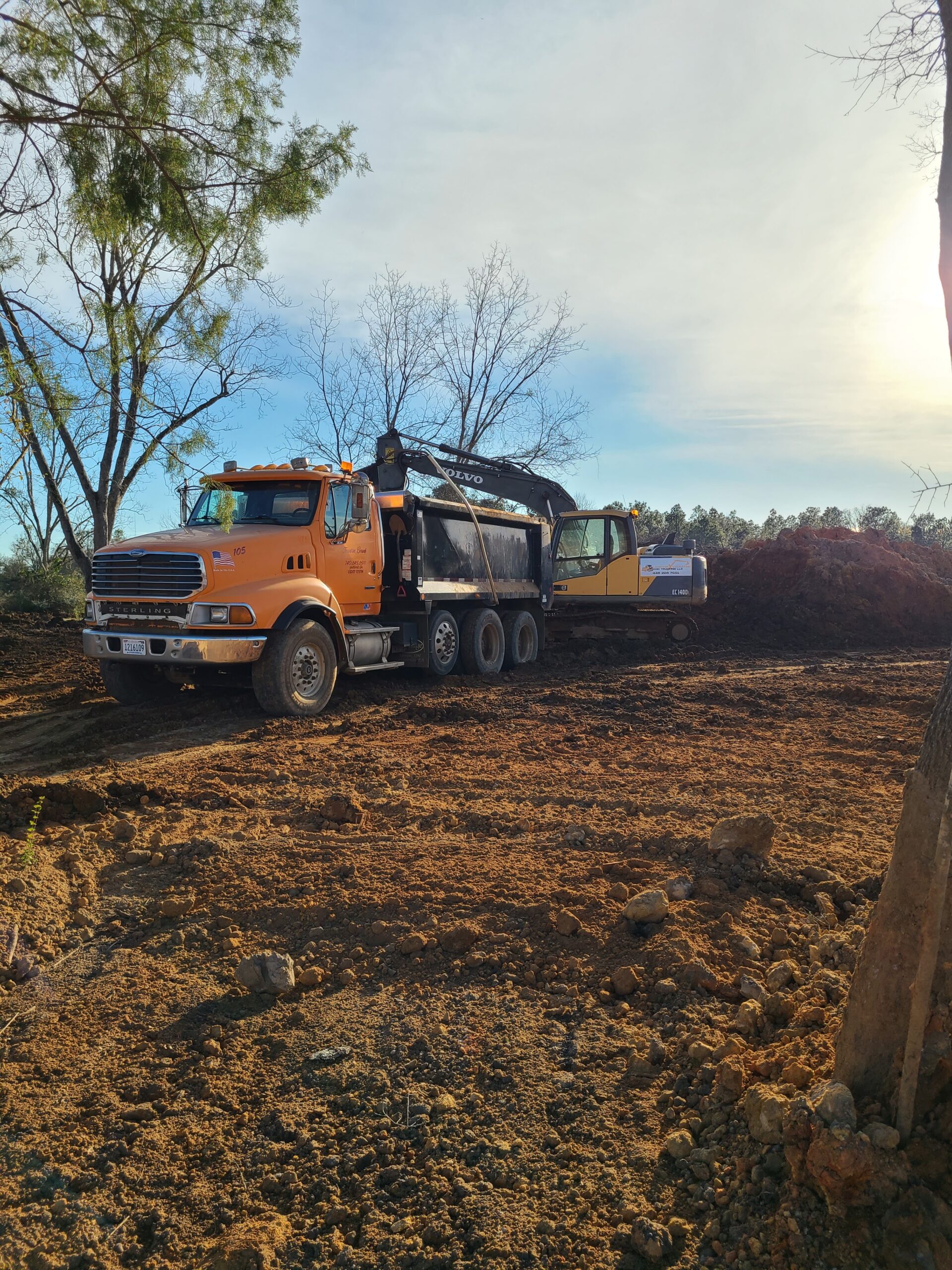 White house by a stream with a view of a forested hill.