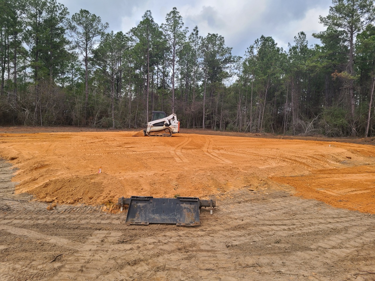 Dirt pile next to an open trench with utility pipes.
