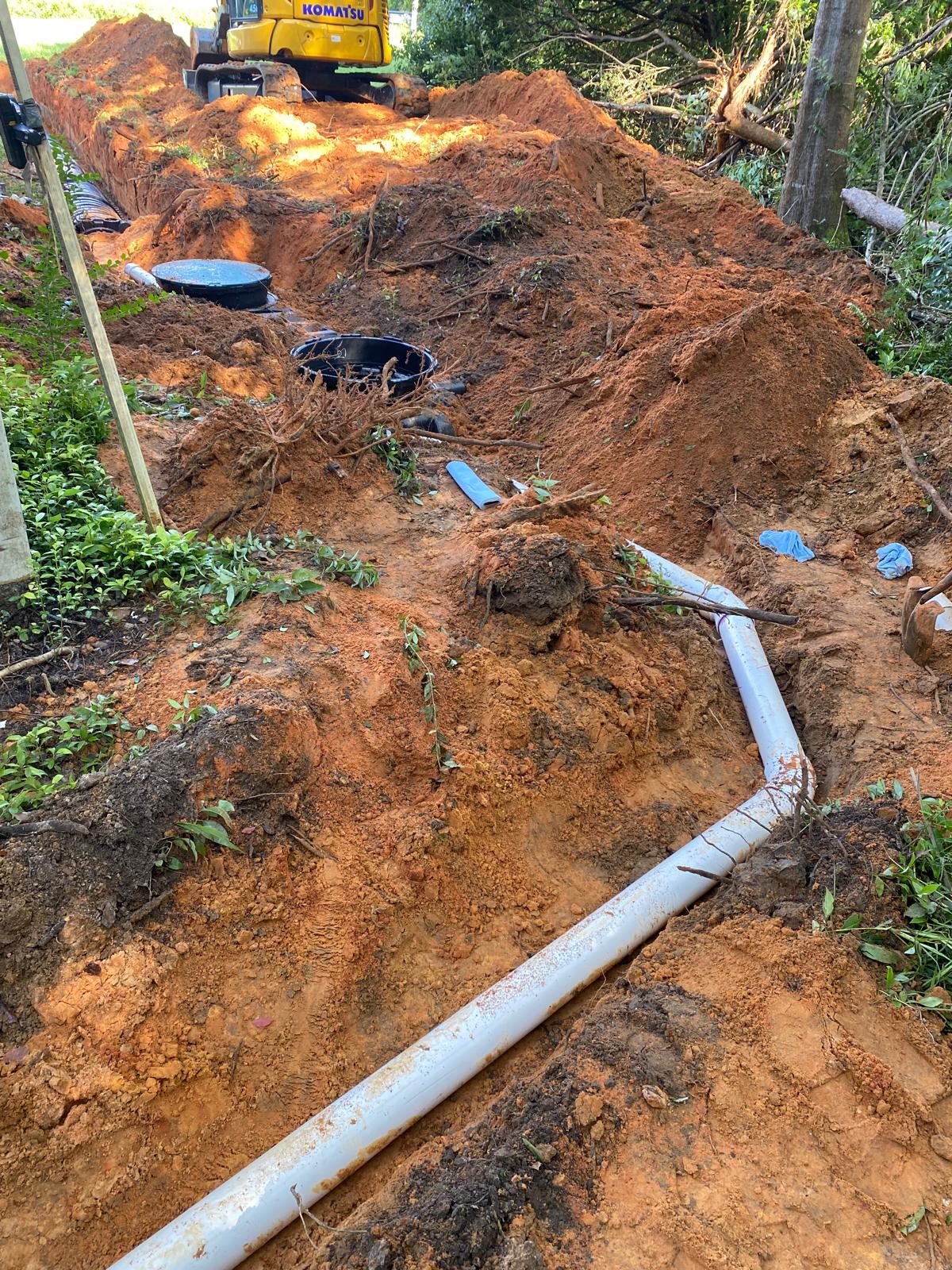 White house by a stream with a view of a forested hill.