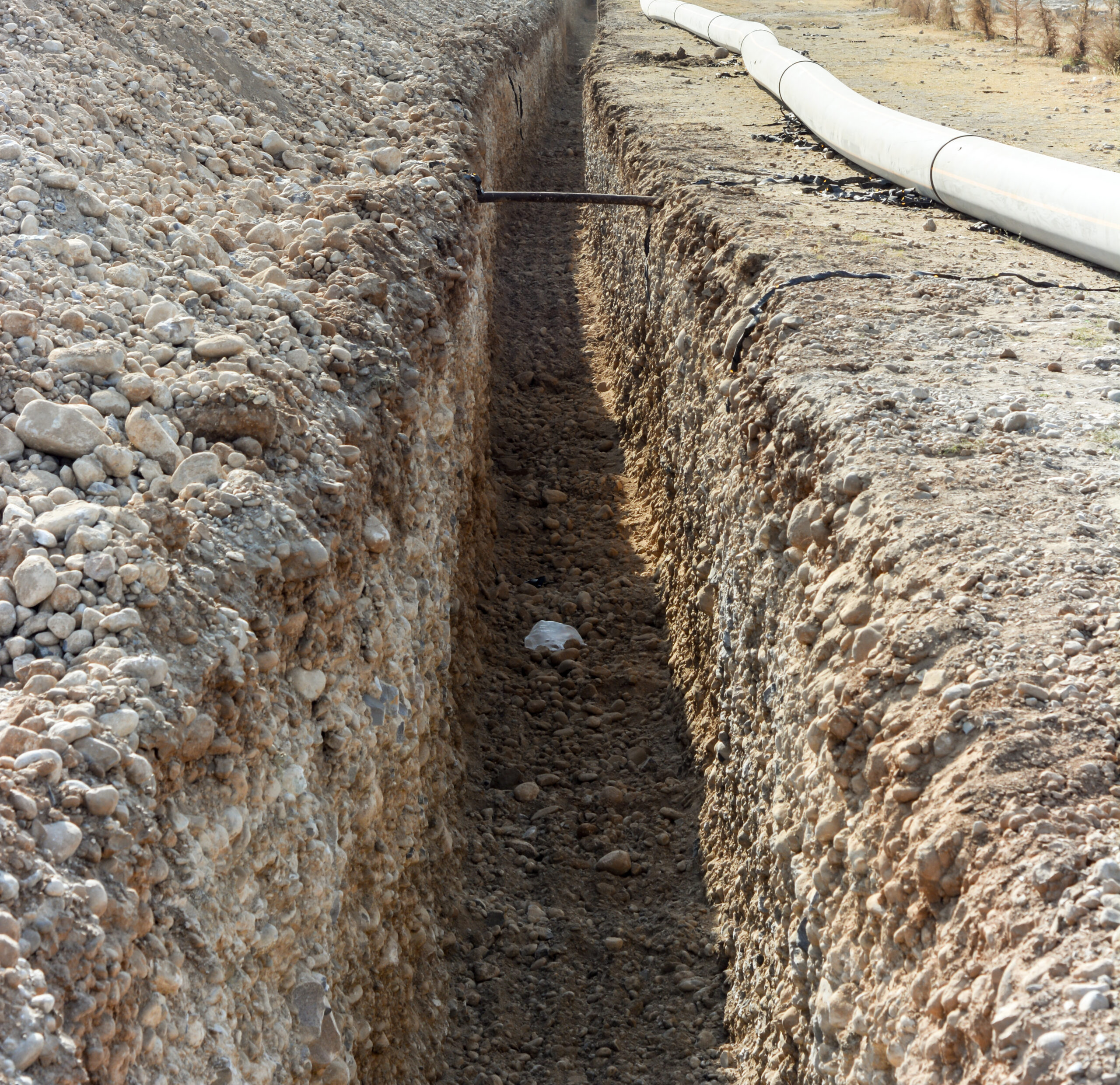 White house by a stream with a view of a forested hill.